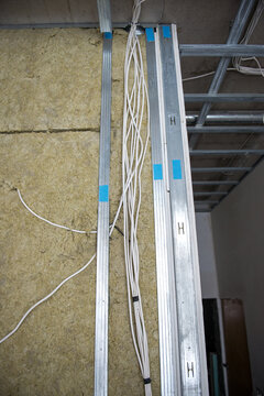 Vertical shot of metal parring and electrical wires on the wall of a building under renovation