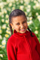 African American mixed race girl smiling standing in a field of daffodils