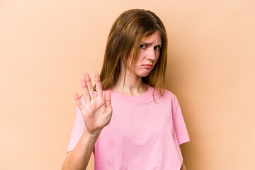 Young English woman isolated on beige background rejecting someone showing a gesture of disgust.