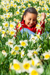 African American mixed race girl sitting playing in a field of daffodils