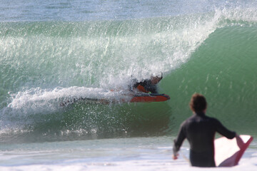 Man looking how another man surfing in a huge wave.