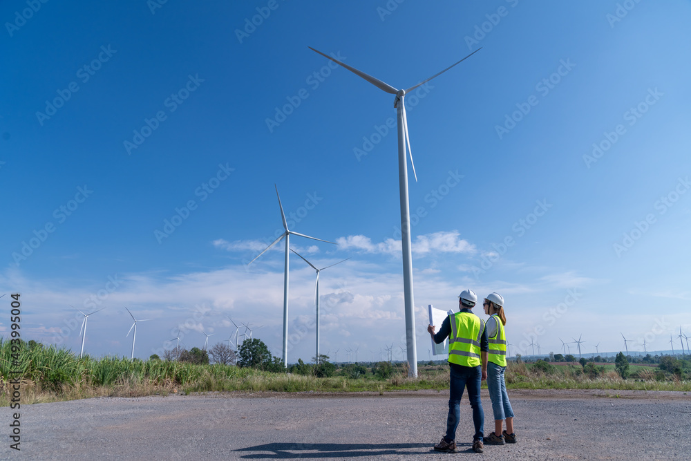 Wall mural engineer wearing uniform ,helmet hold document inspection work in wind turbine farms rotation to gen