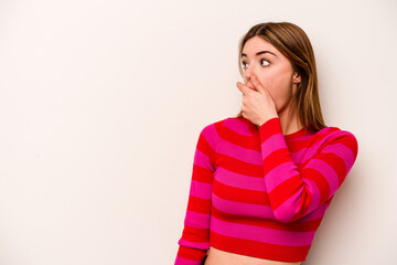 Young caucasian woman isolated on white background thoughtful looking to a copy space covering mouth with hand.