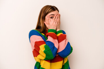 Young caucasian woman isolated on white background blink through fingers frightened and nervous.