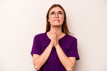 Young caucasian woman isolated on white background holding hands in pray near mouth, feels confident.