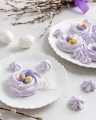 Happy Easter card. Easter meringue nests with eggs candies on the plate on the table with bouquet of willow. Side view, holiday greeting card, confectionery concept