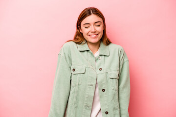 Young caucasian woman isolated on pink background laughs and closes eyes, feels relaxed and happy.