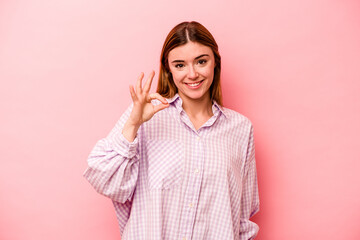 Young caucasian woman isolated on pink background cheerful and confident showing ok gesture.