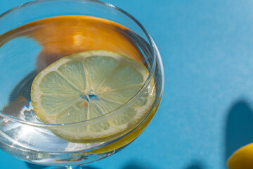 Glass with lemon and lemons on a blue background. The concept of freshness and relaxation