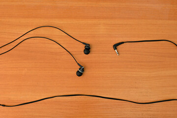 wired headphones tangled in a knot, on a wooden background