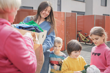 A senior woman gives Ukrainian family of refugee clothes and toys to support them because they had...