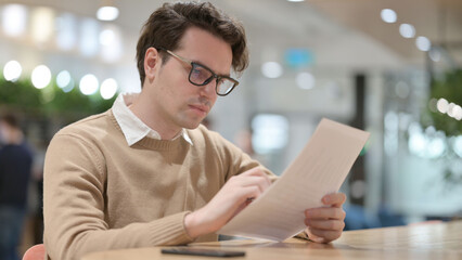 Young Man Reading Documents in Office 