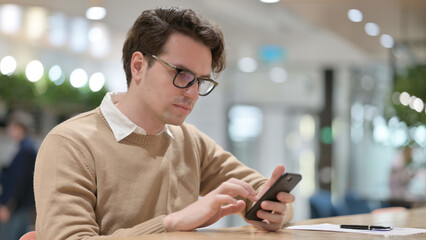 Young Man using Smartphone in Office 