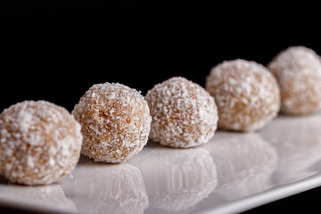 Beautiful sweets with coconut on a white plate on a black background