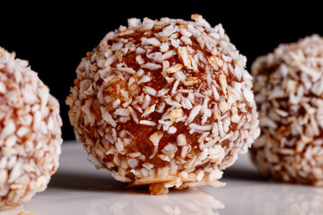Beautiful sweets with coconut on a white plate on a black background