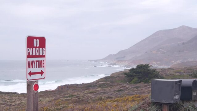 No parking any time road sign on pacific coast highway 1. Postbox or mailbox, Cabrillo road. Ocean sea waves on Garrapata beach, California, Big Sur nature trail, USA. Mountains, foggy misty weather.