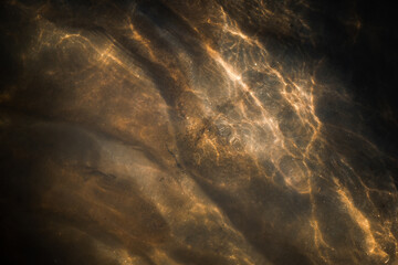 Art of nature - the sun shining through the water in a stream down to the ground