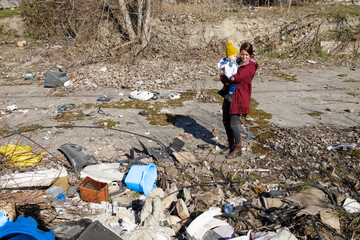 A mother watching destroyed things with a child in her arms