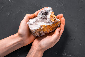 Hands holding natural mineral rock or shiny gemstone