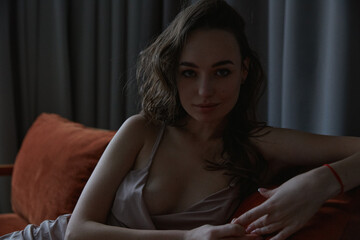 Obraz premium Attractive brunette woman posing in studio laying on sofa fashion style