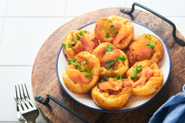 Yorkshire pudding. Traditional English Yorkshire pudding with salmon and radish microgreens side dish on white plate and light grey background table. Top view.