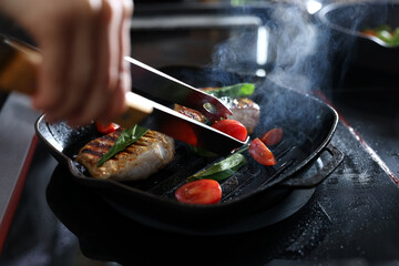 Professional chef cooking meat on stove in restaurant kitchen, closeup