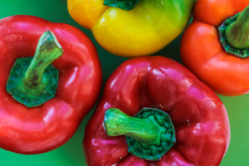 yellow, orange and red peppers on a green background, top view, texture of colorful vegetables 