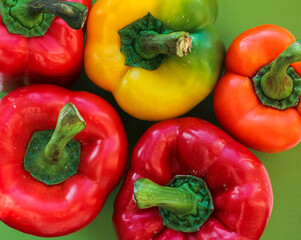 yellow, orange and red peppers on a green background, top view, texture of colorful vegetables 