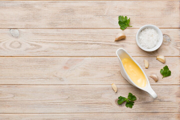Gravy boat with tasty cheese sauce on table background. top view