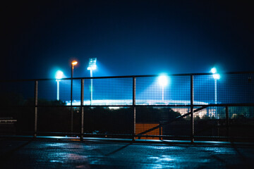 Field with mesh wire illuminated by the blue led street lights in the background at night