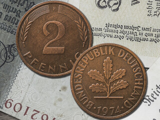 Top view of the front and back of a historic West Germany pfennig coin on a paper background