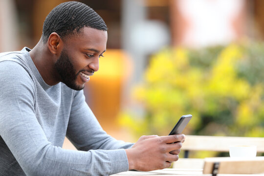 Happy man with black skin using phone in a coffee shop