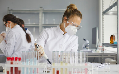 Scientist working in modern pharma or biotech laboratory. Serious pharmacist in PPE mask and...