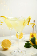Delicious bee's knees cocktail with ice and lemon twist on white table