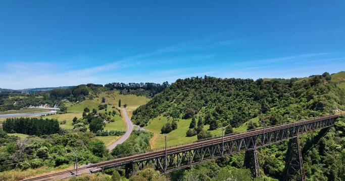 Flying over Mangaweka rail bridge towards highway lush fields - New Zealand