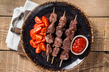 Grilled Beef veal shish kebab Skewers or Shashlik in a plate with tomato. Wooden background. Top...