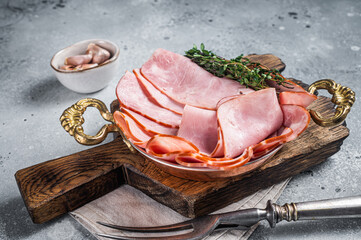 Slices of square sandwich ham with herbs in skillet. Gray background. Top view