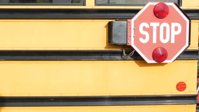 Red stop sign, yellow school bus in California, USA. Traffic warning on passenger schoolbus or shuttle in America. Public transportation safety on road. Caution or attention signage. Education concept