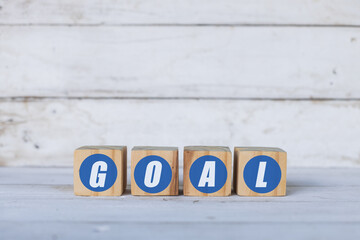 goal concept written on wooden cubes or blocks, on white wooden background.