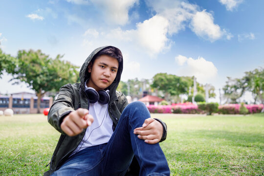 Wide angle shot of teenager sitting in lawn green grass at the park, lifestyle portrait concept,