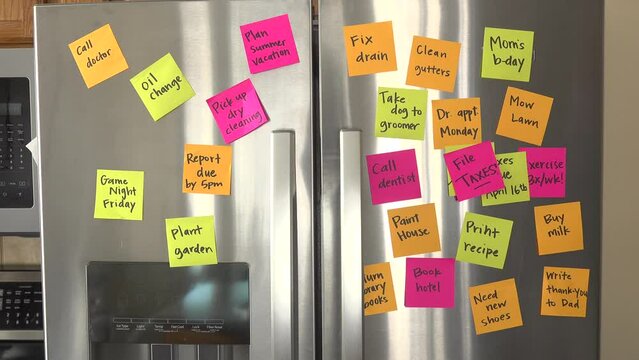 Refrigerator Door Filled With Reminder Notes and Hand Adds File Taxes Memo Over File Taxes Due April 16th Memo