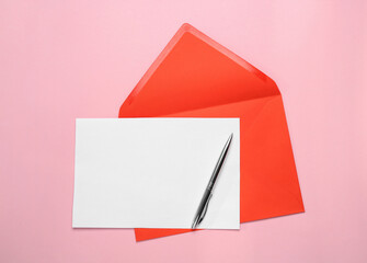 Red envelope with blank letter and pen on pink background, top view