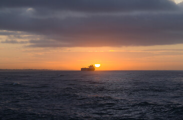Naklejka na ściany i meble cargo ship at dawn on the horizon of the caribbean sea