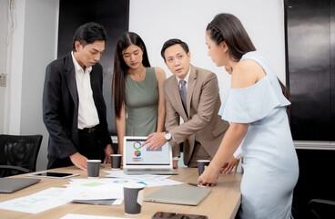 Young businessman present graph report and statistics of profit with finance on laptop computer in meeting conference room at office, executive planning and investment with employee, business concept.