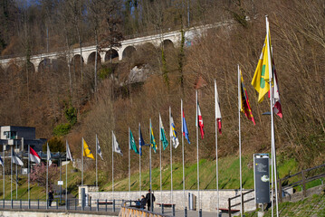 Flags of all Swiss Cantons at border of natural pool of famous Rhine Falls on s sunny spring day....