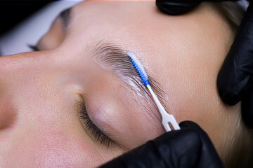 the master has a comb for laminating eyebrows in the palm of his hand