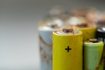 Closeup of used battery with traces of rust and corrosion, selective soft focus. Macro shot of lot of old leak batteries. Electronic hazardous waste, recycling concept 
