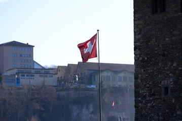 Famous Rhine Falls Swiss flag on top of rock on a sunny spring day. Photo taken March 5th, 2022, Neuhausen am Rheinfall, Switzerland.
