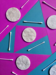 Pattern of cotton swabs for cleaning ears and cotton pads for removing make up and washing face on colored pink and blue mosaic background