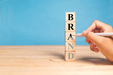 hand is using a black pen rewrite over the faded word " brand " make it clearly visible as re-branding concept